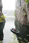 Liten båt på stille vann mellom bratte fjellvegger i Fantahålå i Lysefjorden.