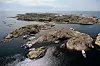 Luftfoto av Tisler med nakne svaberg, små skjær og båter ved kysten.