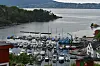 Utsikt over småbåthavn ved fjord med skogkledde åser i bakgrunnen