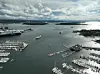 Luftfoto av havnebasseng med småbåthavner, ferger og øyer i bakgrunnen.