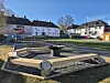 Lekeplass og bålplass i grøntområde mellom lave boligblokker.