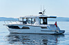Hvit motoryacht på rolig vann under klar himmel.