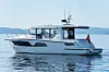 Hvit motoryacht på rolig vann under klar himmel.