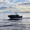 Svart drone fra River med nummer 6664 på stille vann under dramatisk skydekke.