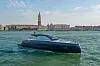 Mørk blå Beneteau-yacht på vannet foran Venezias historiske bygninger og klokketårn.