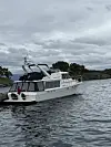 Hvit motorbåt ligger ankret ved en liten øy under overskyet himmel.