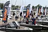 Buster-båter og besøkende ved en marina med flere merkevareflagg.