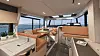 Lyst yachtinteriør med sittegrupper, spiseplass og panoramavinduer.
