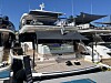 Stor hvit yacht fortøyd ved en marina, omgitt av andre båter under blå himmel.