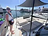 Kvinne med solbriller på en båt i en solfylt marina.