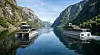 Fjord med speilblankt vann, bratte fjell og flere fortøyde båter.